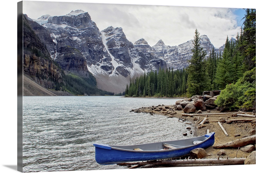 Moraine Lake, Banff National Park, Alberta, Canada. This image portrays a canoe resting along the water's edge with the st...