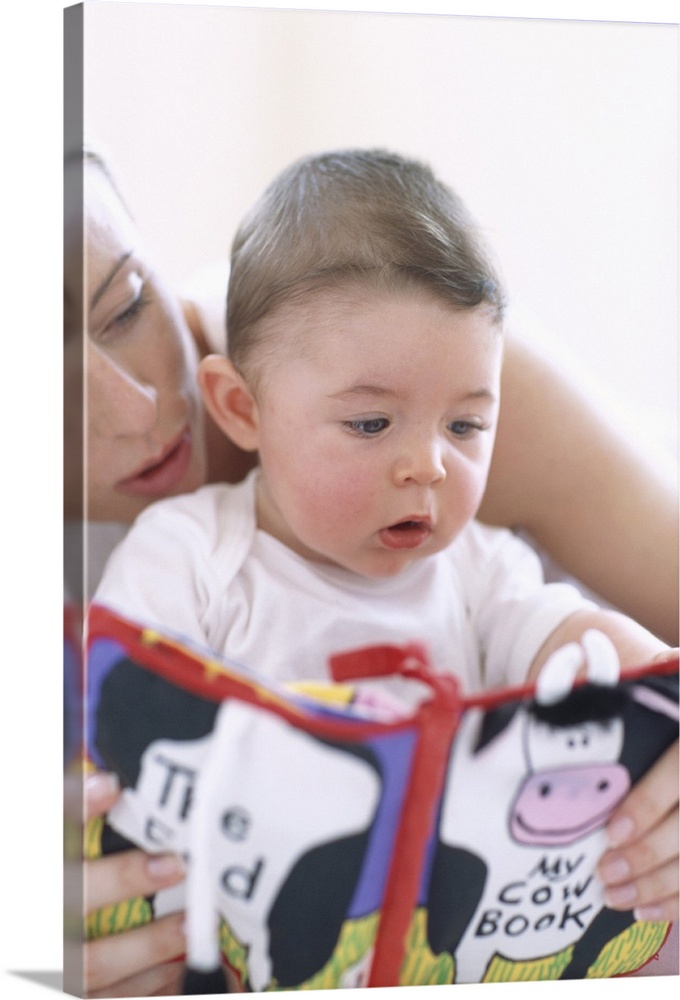 Mother reading to baby boy. Faces of a mother reading aloud to her 6-month-old baby boy. Describing pictures in a book hel...