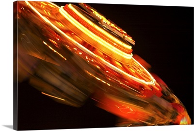 Motion blurred shot of red lights on an amusement park ride at night.