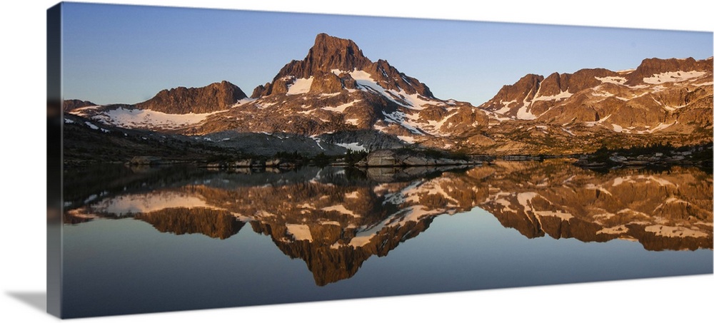 The snow capped peaks of the Sierra Nevada get cleanly reflected on a calm but cold sunrise at Thousand Island Lake in the...