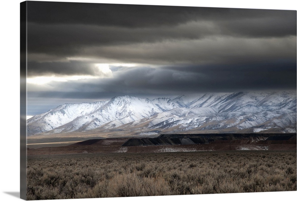Open pit mining in Northern Nevada with mountain range in background.