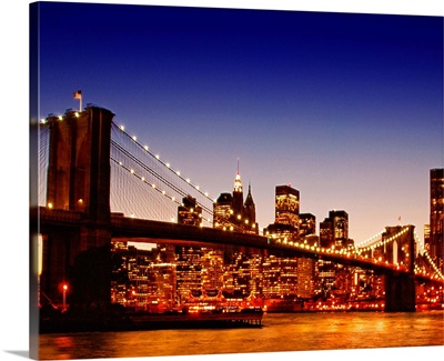 New York cityscape with bridge over river during sunset.