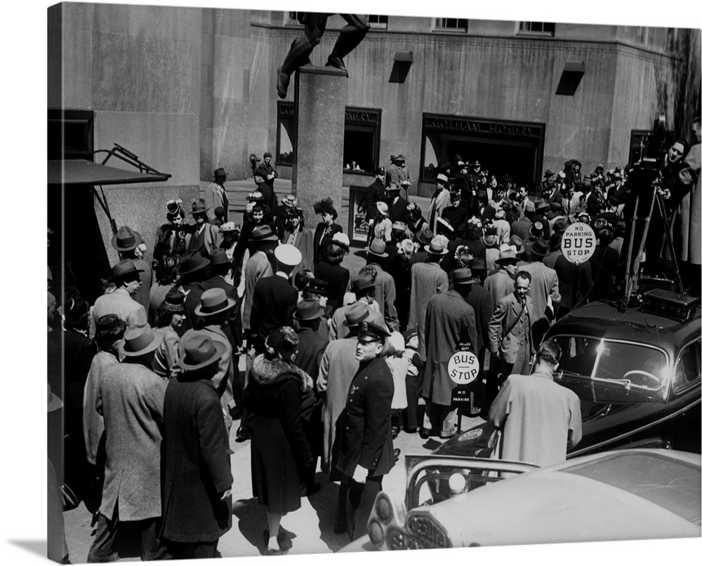Crowds passing the bronze statue of Atlas in front of the Rockefeller Center on Fifth Avenue, New York City, circa 1950. T...
