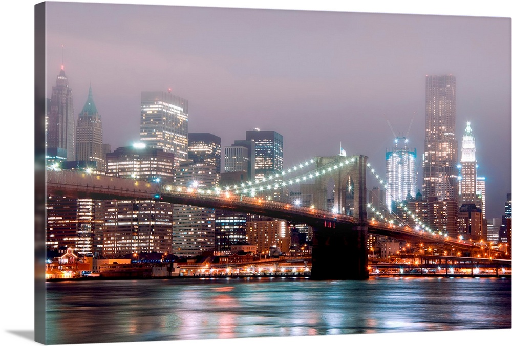 A misty night scene illuminated by urban lights of downtown Manhattan photographed from the Brooklyn shore.