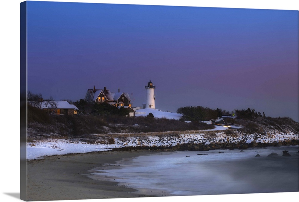 Nobksa lighthouse photographed after a fresh snowfall on Cape Cod.  Image was taken at dusk and the glow from the window l...