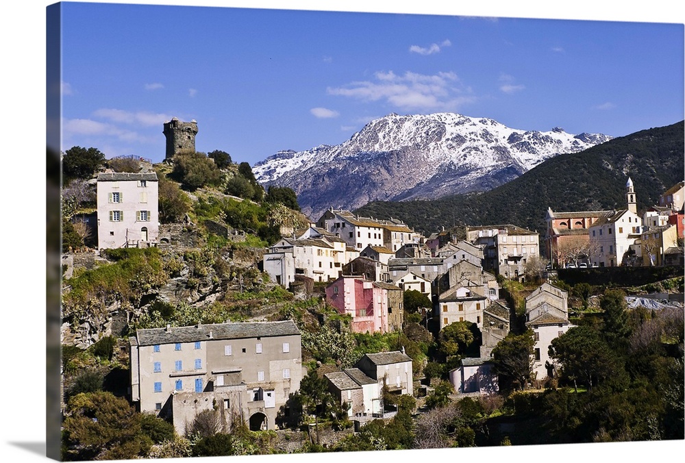 Nonza village (Corsica, France) with its famous tower in the foreground. In the background, the majestic, snow-covered mou...