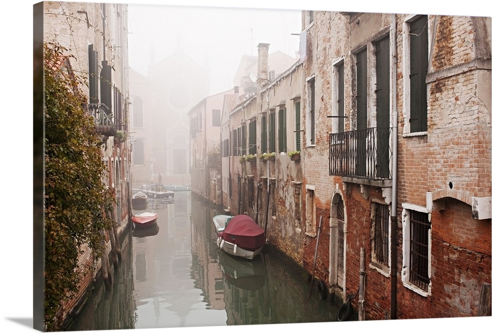 Autumnal mists lie over the water of a small backwater canal on a quiet November morning in Venice.