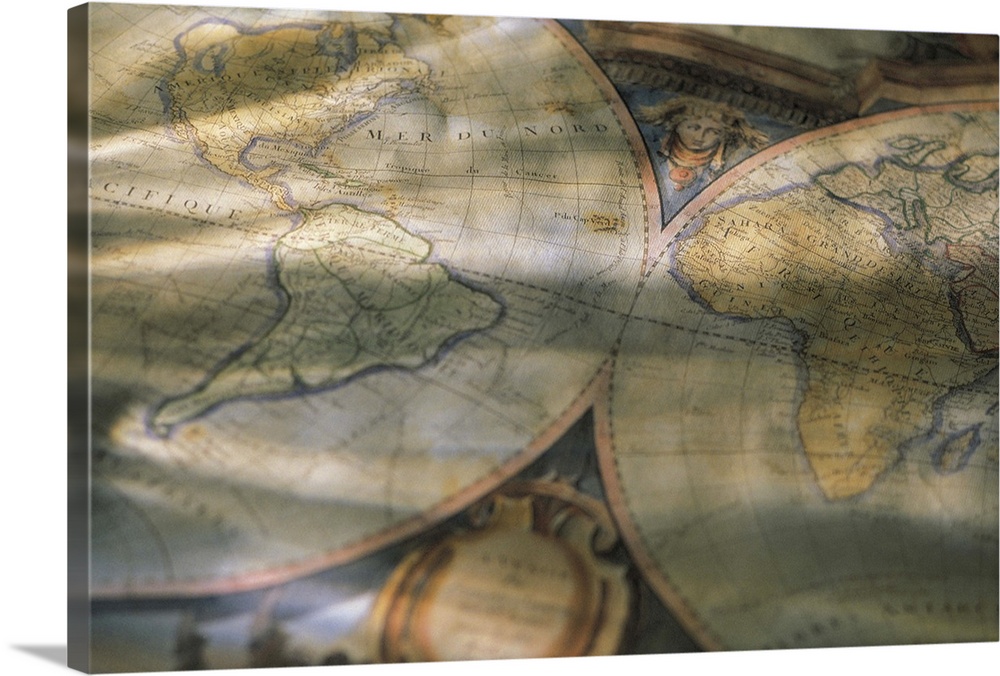 A picture is taken of an antique map of the world that is partially crinkled and sitting in a shaded room.