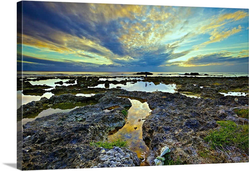 Labyrinthine coral reefs on a cloudy evening with calm water in tidal pools reflecting the sky and clouds spreading out fr...