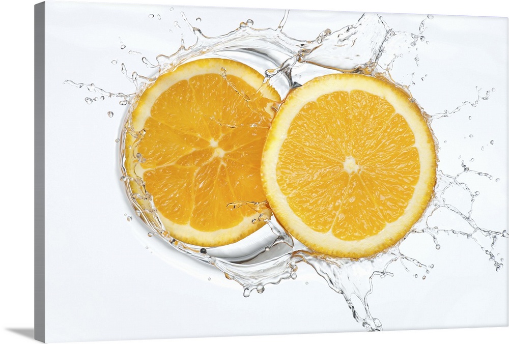 Two healthy thin fresh organic slices of orange splashing into a pool of clean clear refreshing water in studio on a white...