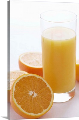 Oranges by orange juice in glass, close-up
