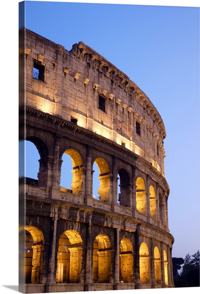Veridical photograph of the Roman Coliseum at dusk with the lights illuminating the arched windows.