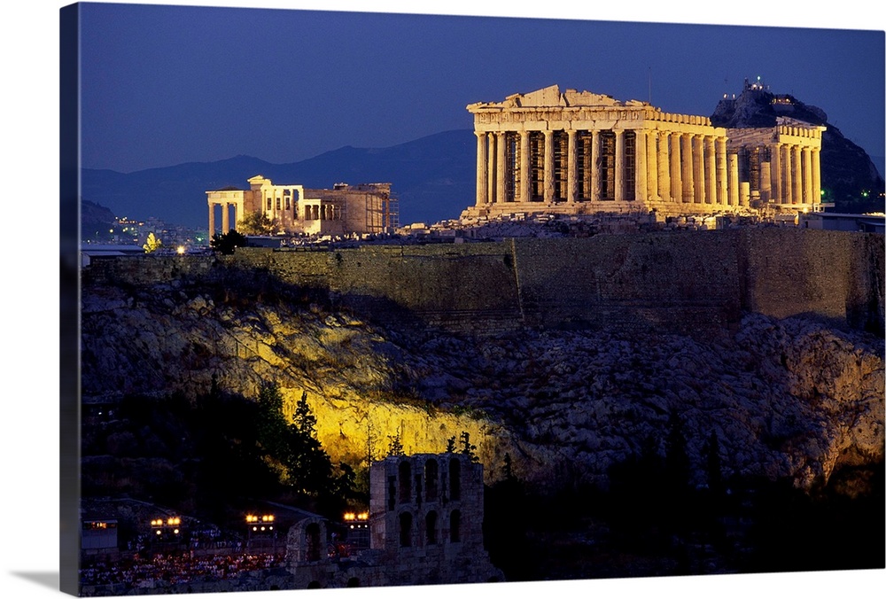 The Parthenon and surrounding temples of the Acropolis sit illuminated, overlooking Athens.