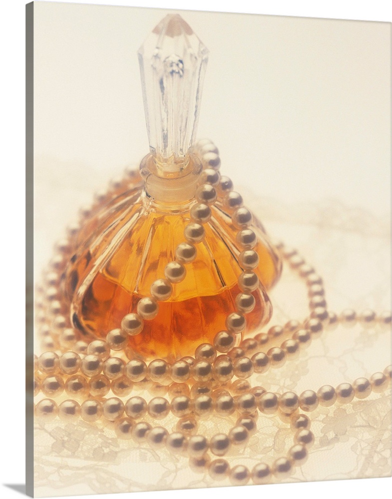 Pearl necklace draped around a perfume bottle