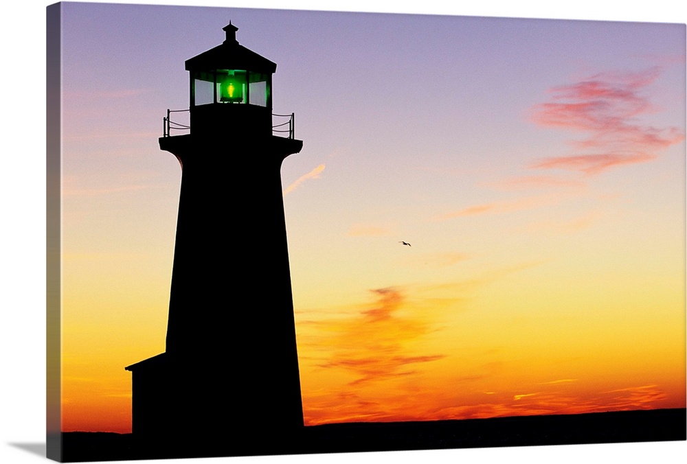 Silhouette of Peggy's Cove Lighthouse at sunset in Nova Scotia.
