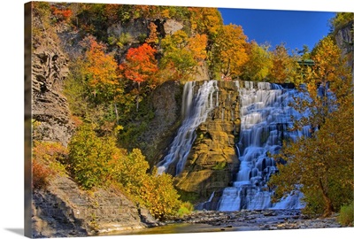 People stand at the crest of Ithaca Falls during the beautiful fall foliage season