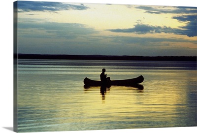 Person on a canoe in a lake at sunset