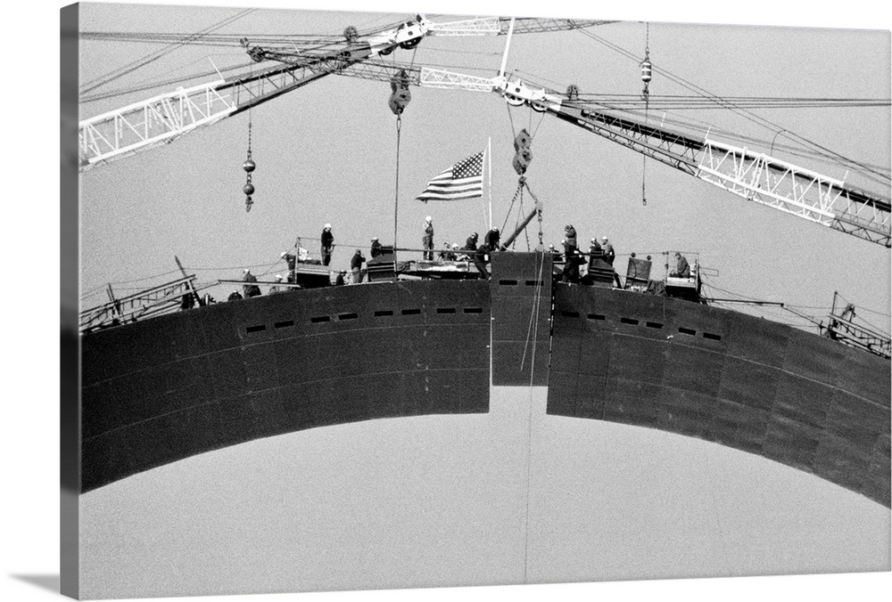 Keystone Set. St. Louis. With the American flag fluttering above their heads, workmen expertly slip the 10-ton keystone se...
