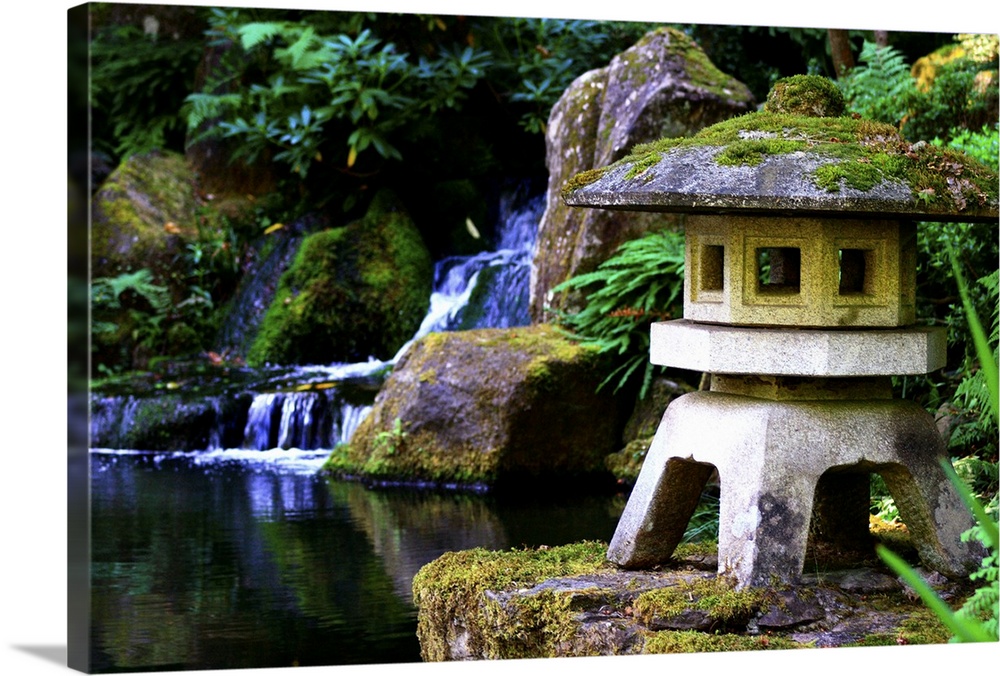 Japanese garden. A little stone pagoda with a waterfall in the background. Lush vegetation.