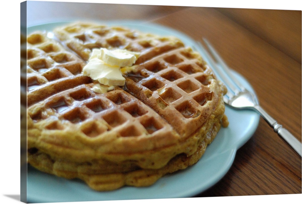 Homemade pumpkin waffles on a blue plate for breakfast recipe with fork.