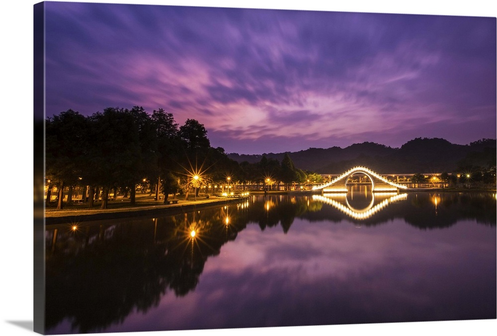 Purple tone prior to sunrise with light up arch bridge and its reflection in the water.
