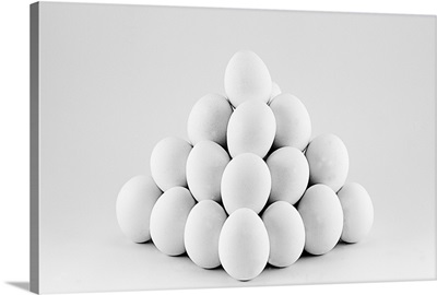 Pyramid of white eggs on bright gray background.