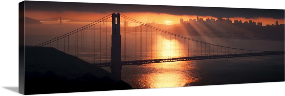 Golden Gate bridge, with sun rays over it and reflection in water.