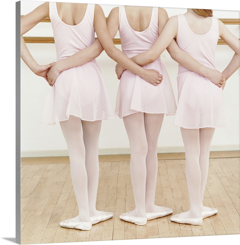 Rear View of Three Young Ballet Dancers Standing in a Line With Their Arms Around Each Other