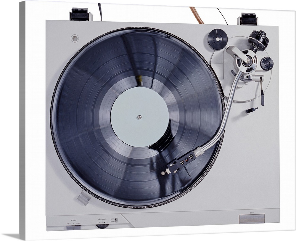 This photograph is taken of a vintage record player looking down at the record as it plays on the turn table.