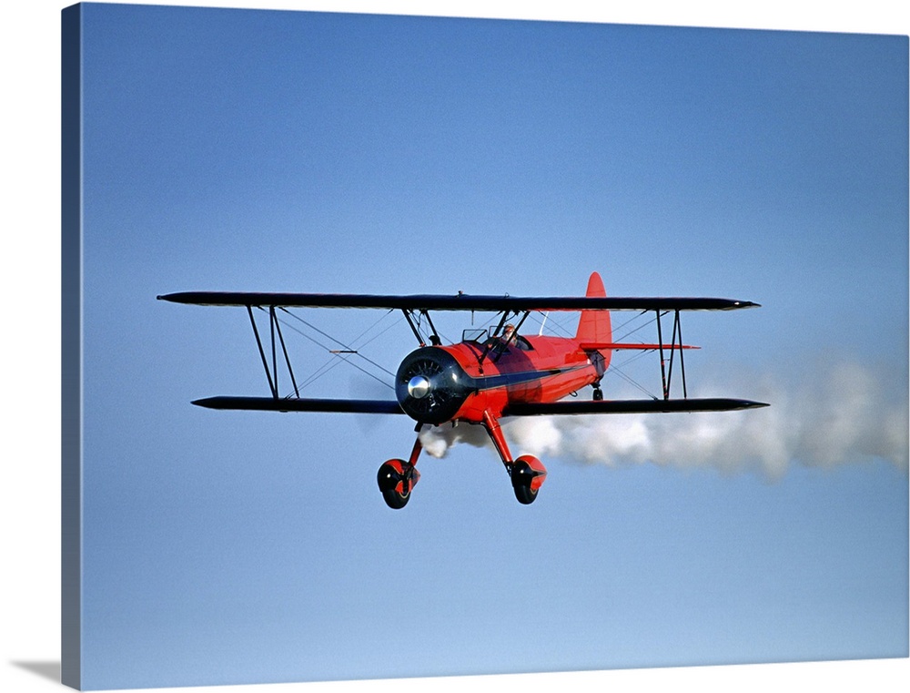 Red 1943 Stearman bi-plane in flight with tail smoke, St. Francis, Kansas, USA