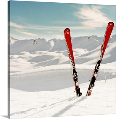 Red pair of ski standing in snow. Mountains in background