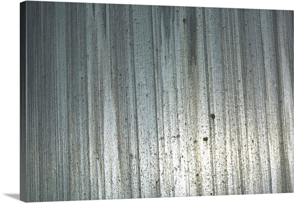 Big, horizontal photograph of a shiny metal surface with vertical streaks and a rough, pitted texture.