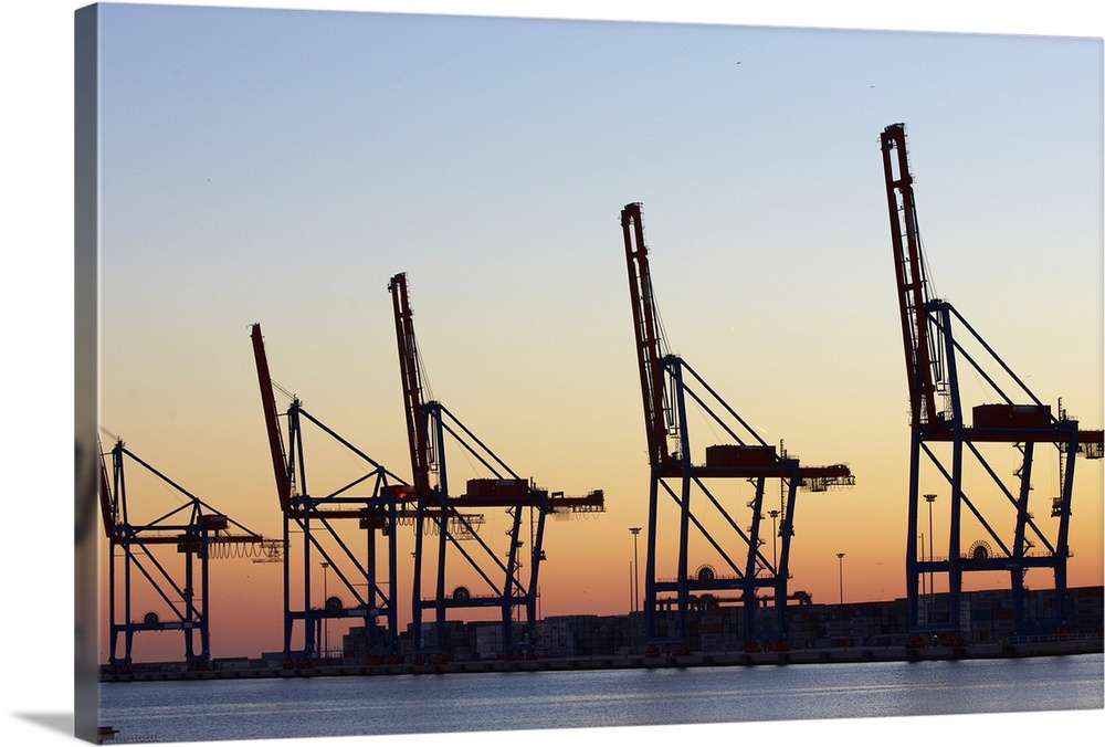 Row of cranes in the dock area of Malaga at sunset