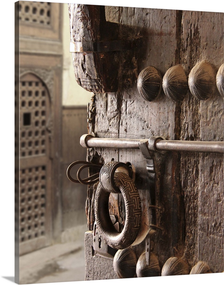 Old and rustic door elaborately decorated with heavy metal details and lock... ajar, with a peek at another, lighter scree...