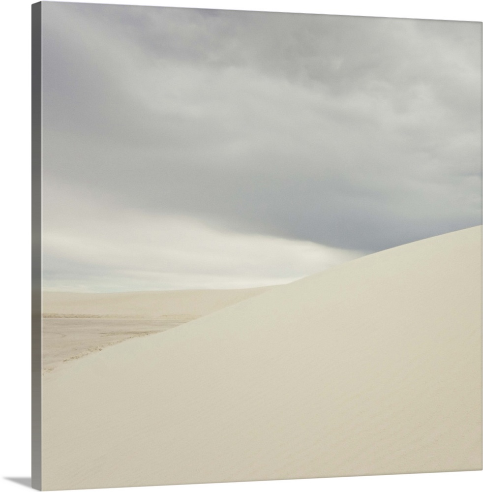 White sand dunes against cloudy sky.
