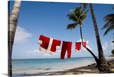 Santa Claus costume hanging on clothesline on tropical beach