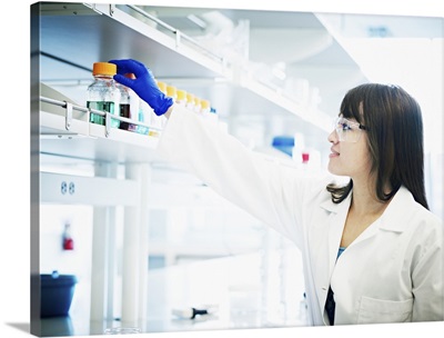 Scientist reaching for bottle of solution in lab