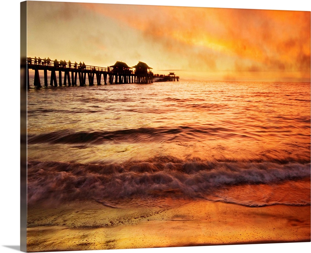Sunset with crowd of people walking on pier, sea fog rolling inmakes orange and gold mysterious atmosphere on water.