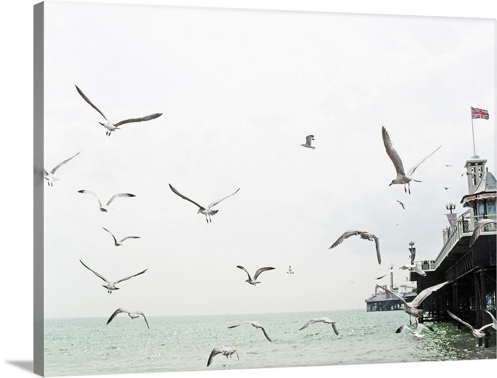 Seagulls flying around Brighton pier with Union Jack mast.