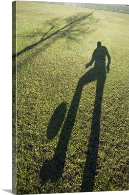Shadow of man kicking soccer ball in the air