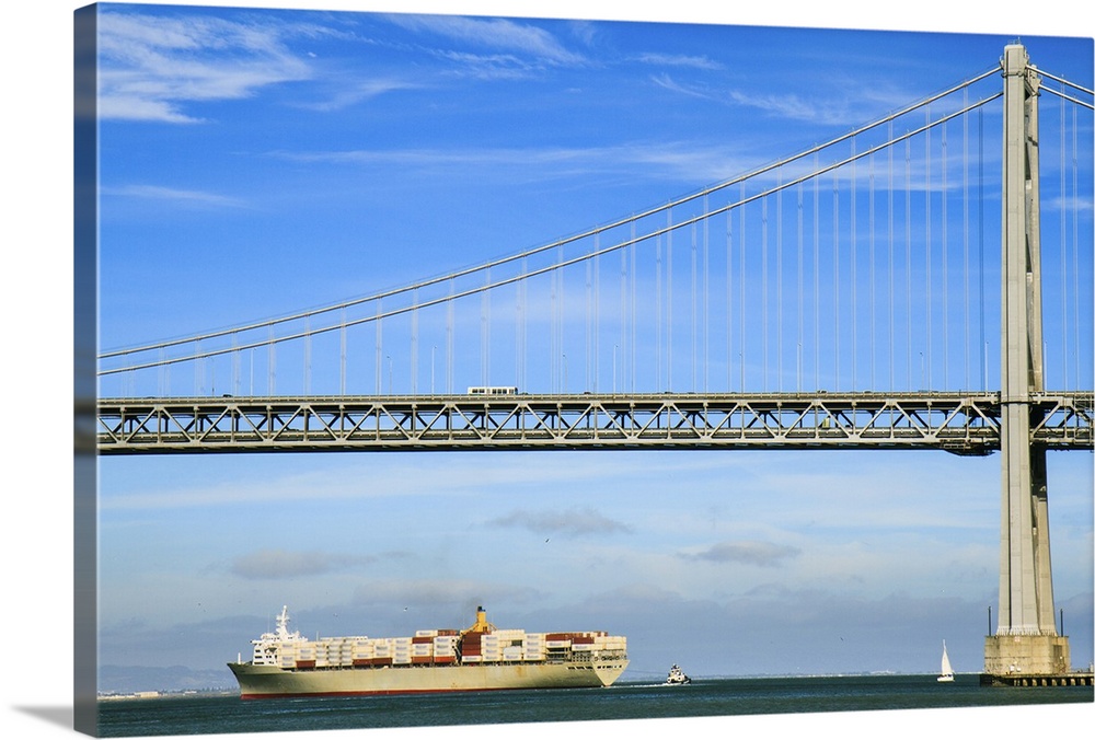 Large cargo ship crossing San Francisco Oakland Bay Bridge (known locally as the Bay Bridge), spanning San Francisco Bay o...