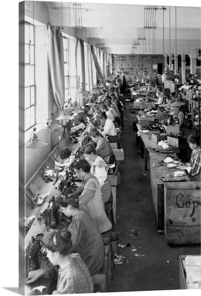 Shoe factory workers sewing on long tables.