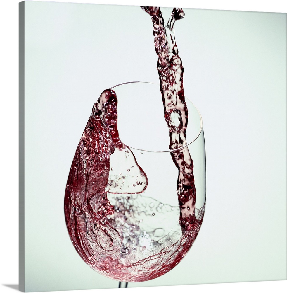 Photograph taken of red wine while being poured into a clear wine glass.