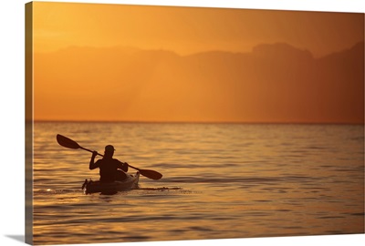 Silhouette of a Woman in a Sea Kayak at Sunset