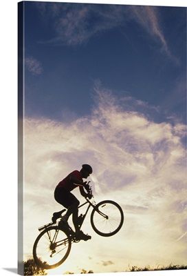 Silhouette of man in mid-air on mountain bike