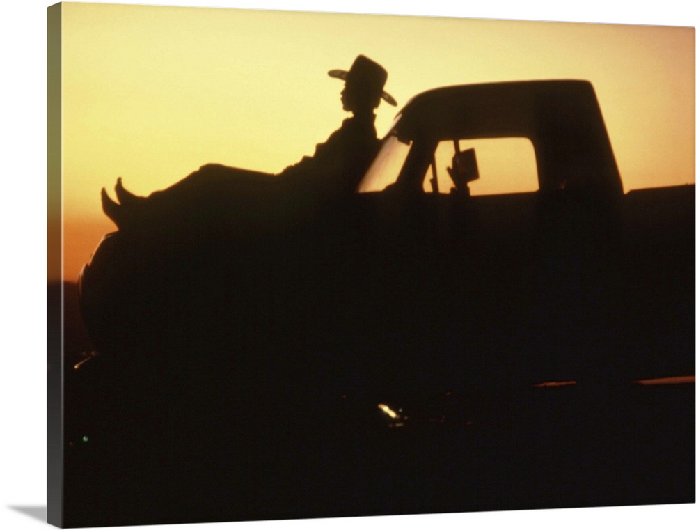 Silhouette of man reclining on hood of truck