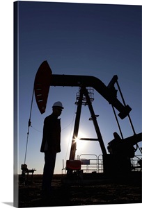Silhouette of oil worker by pump jack on rig image thumbnail