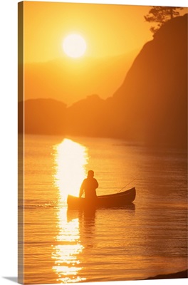 Silhouette of person canoeing at sunset