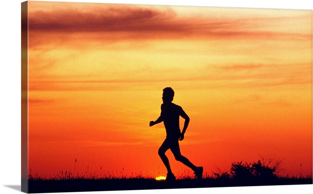 Silhouette of runner on ridge at sunset