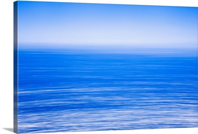 Silky calm blue open sea with fog or mist over water, Blue sky